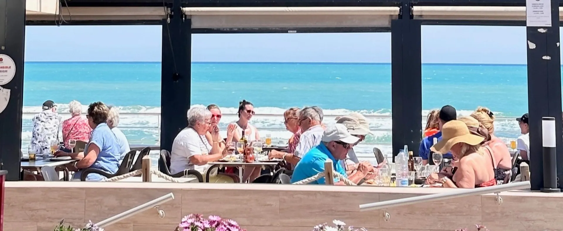 Personas disfrutando en una terraza junto al mar